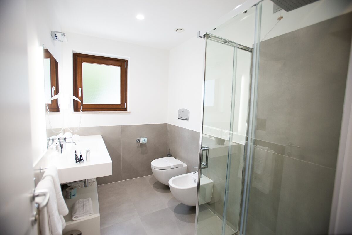Un baño moderno con cabina de ducha de vidrio, lavamanos blanco con espejo y inodoro.