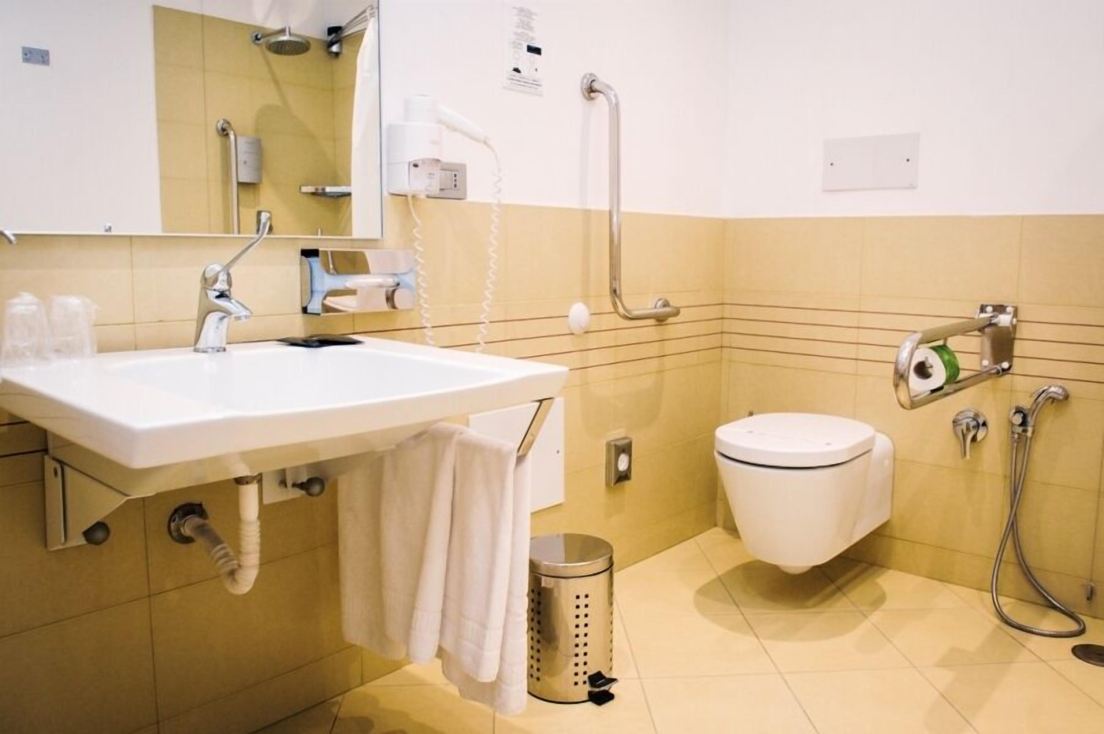 Un baño con lavamanos, espejo, inodoro y ducha.