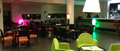 A hotel lobby with multiple seating areas, a bar, and a reception desk.