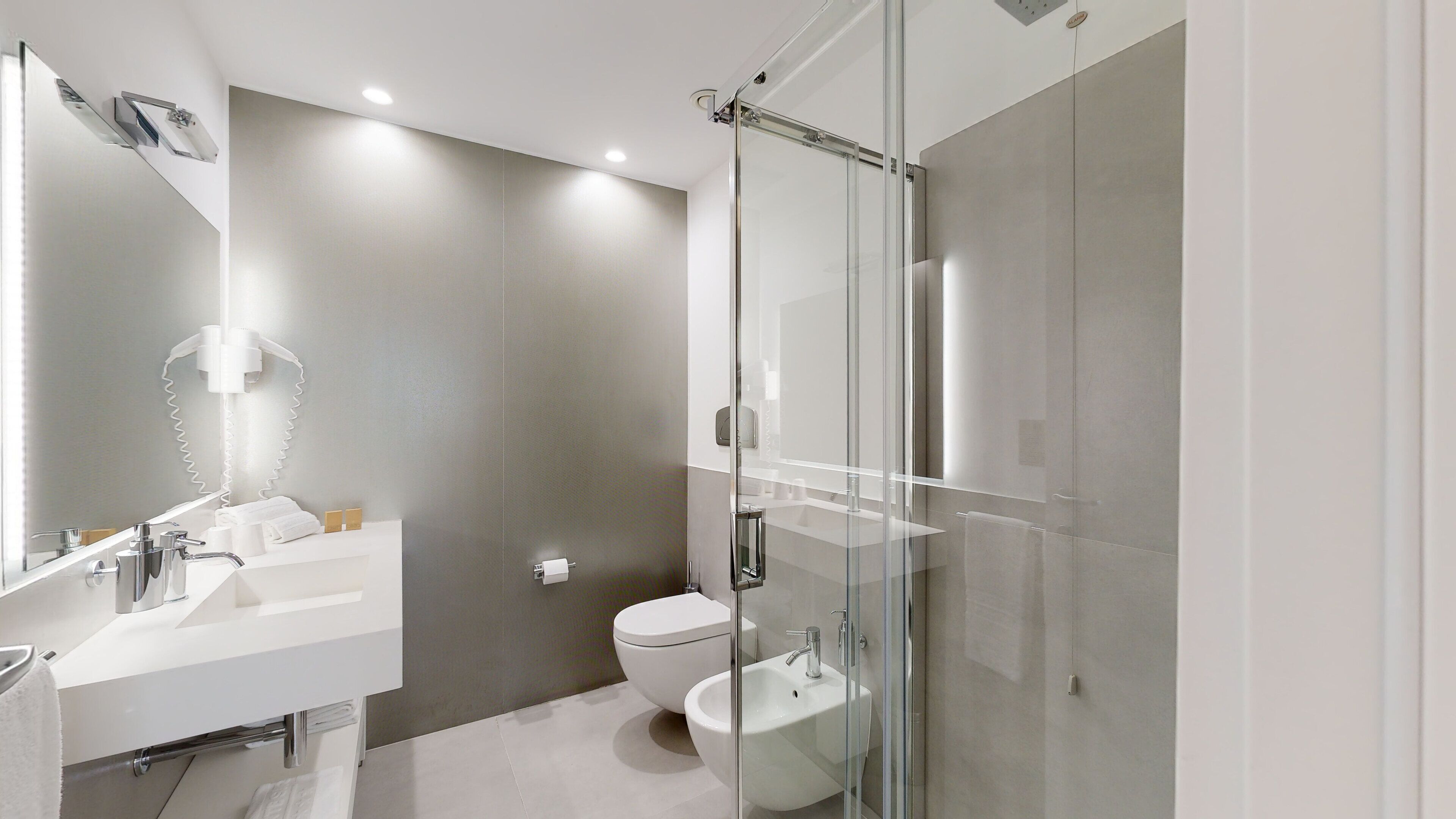 A modern bathroom with a glass shower enclosure, a white sink, and a toilet.