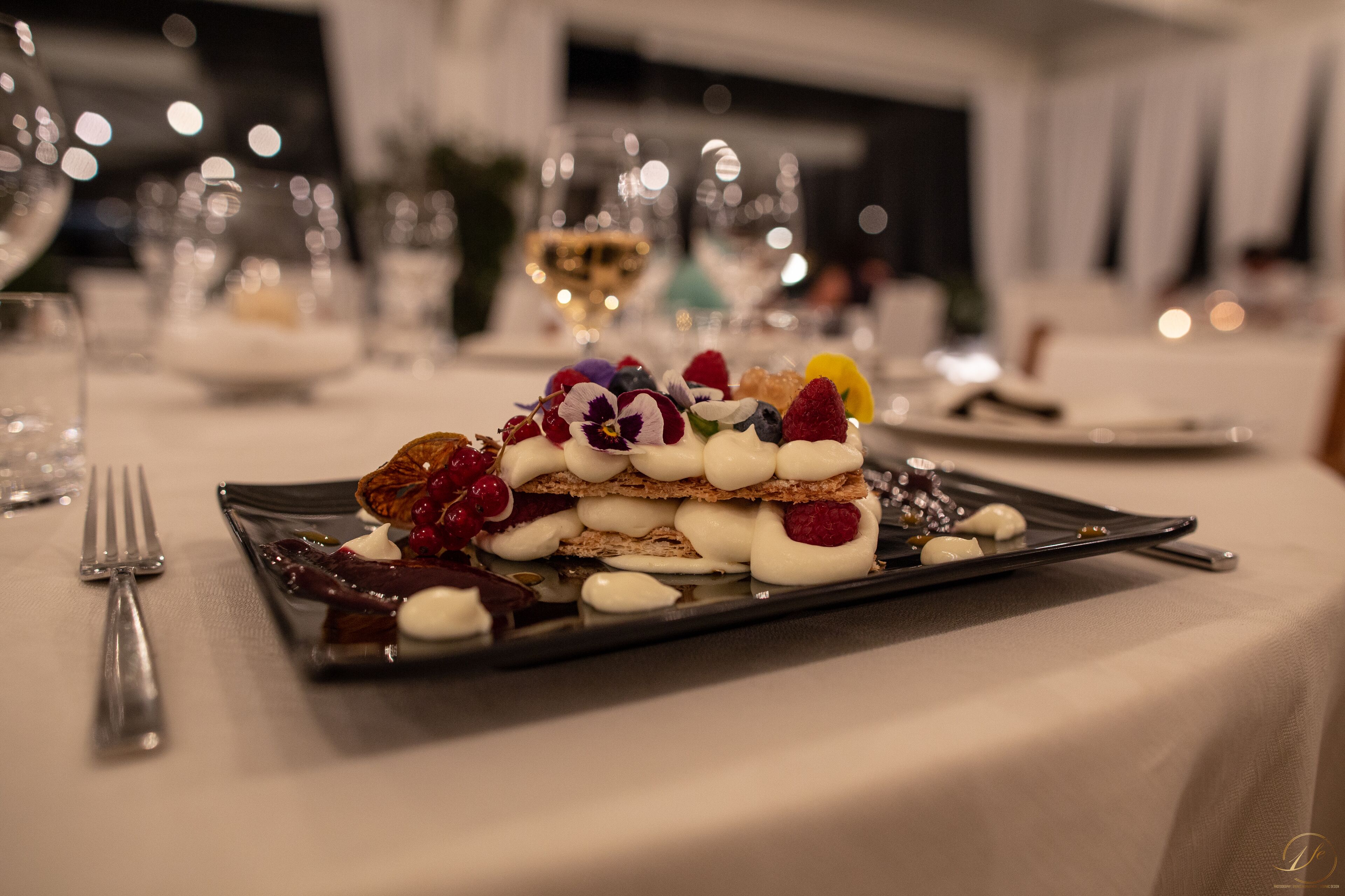 Un piatto dessert con diversi frutti e panna su un tavolo in sala da pranzo.