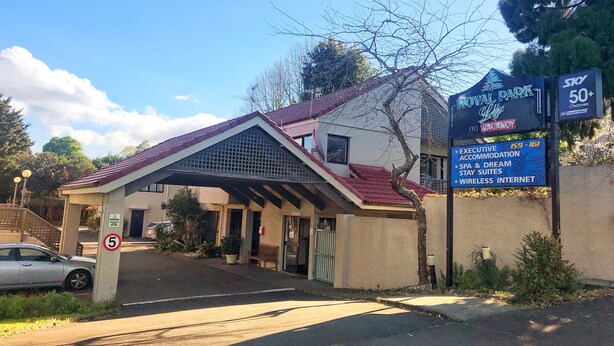 A hotel entrance with a covered walkway, a sign indicating a vacancy, and amenities listed such as executive accommodation, spa, and wireless internet. - Royal Park Lodge (Auckland)