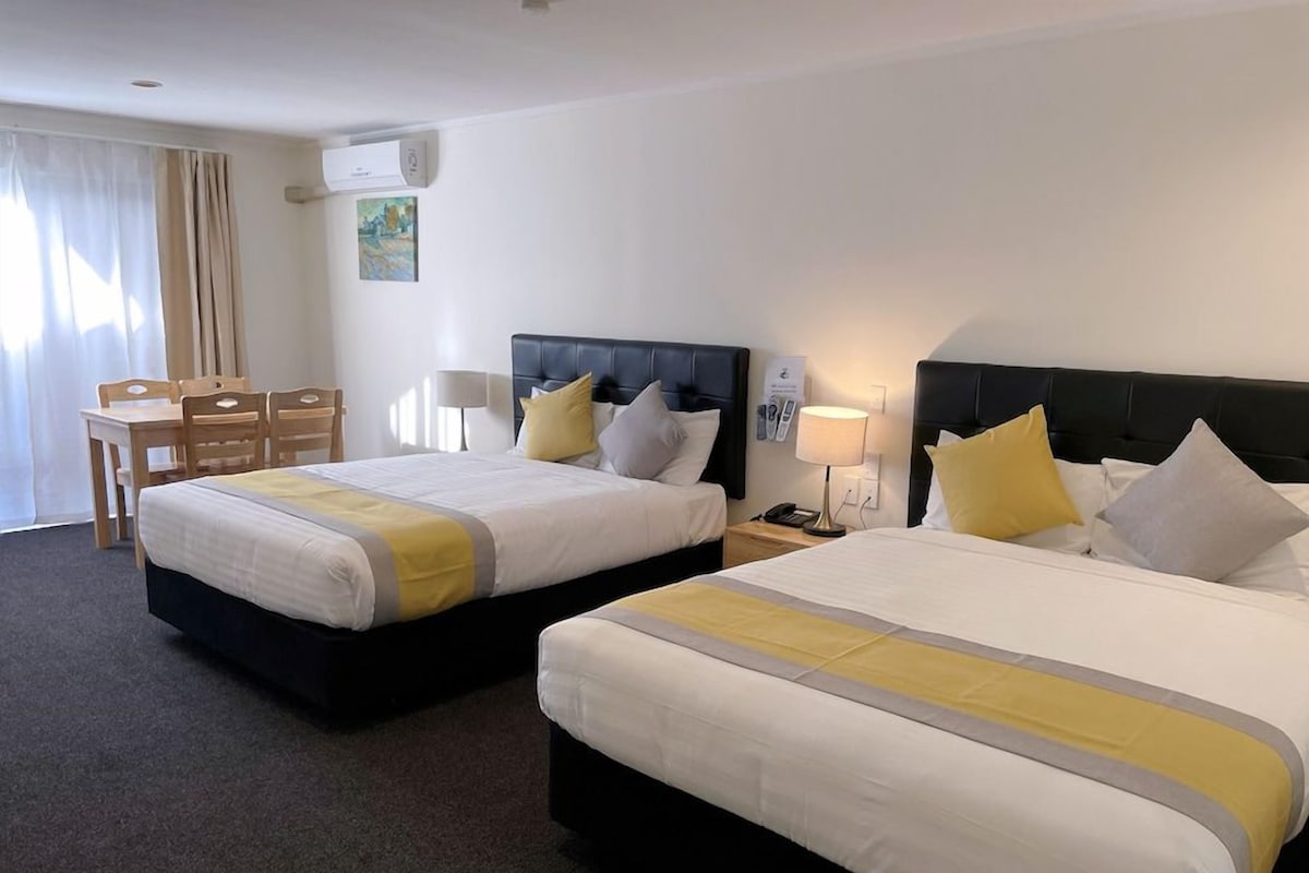 Ein Hotelzimmer mit zwei Betten, einem Schreibtisch und einem Sessel.