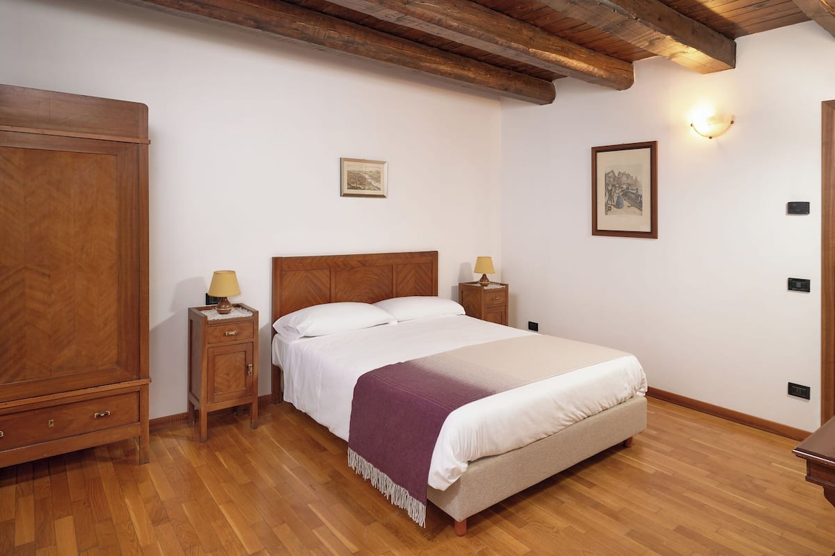 Ein Schlafzimmer mit einem Holzbett, zwei Nachttischen mit Lampen, einem Kleiderschrank und einem Holzboden.