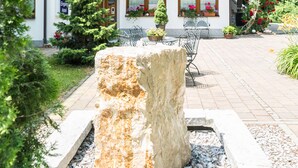 Eine Holzhütte mit Balkonen, die mit Blumen geschmückt sind, eine Steinskulptur im Vordergrund und ein Schild, das ein Hotel anzeigt.