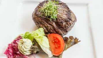 A steak with a garnish of greens and a side salad.