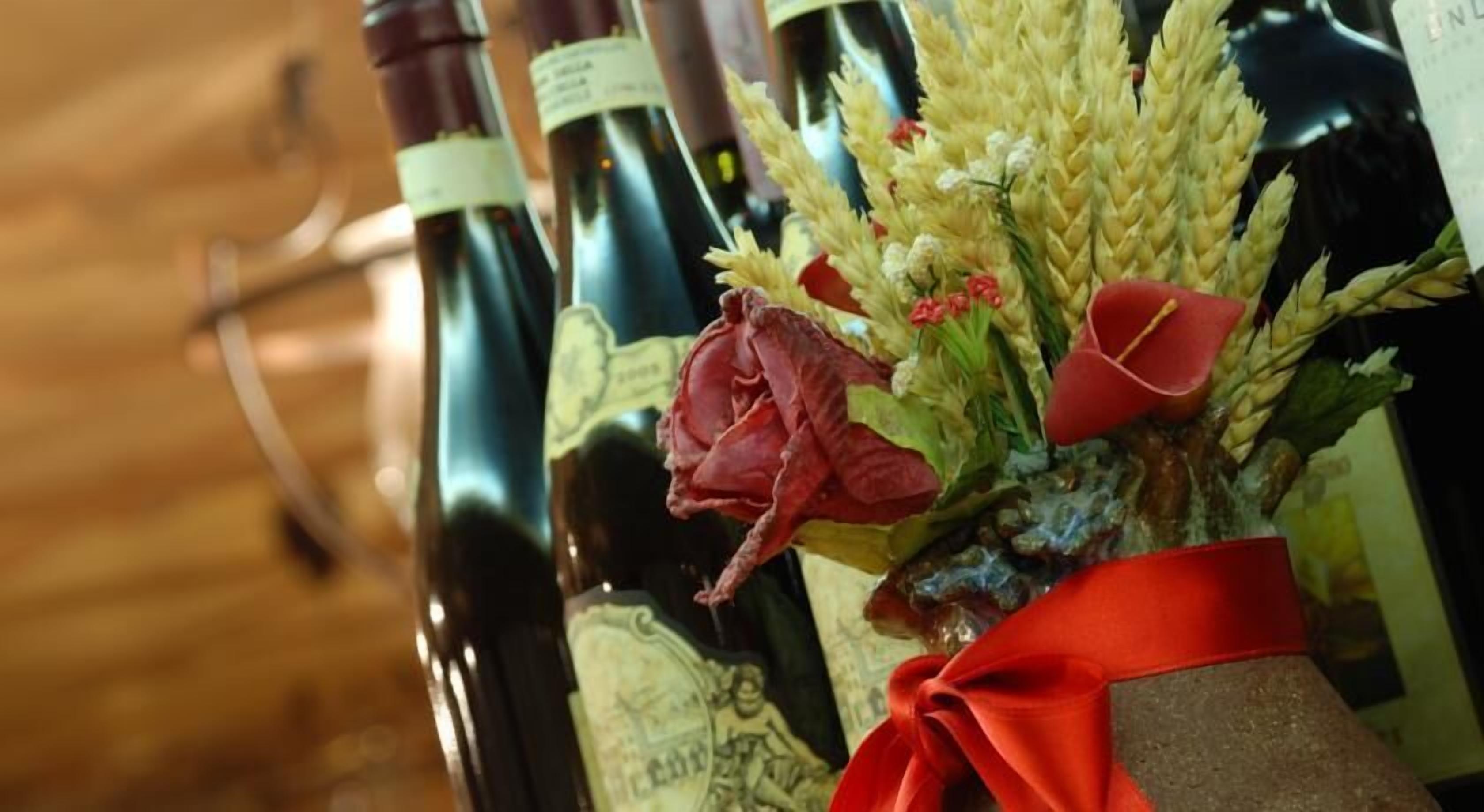 A row of wine bottles with labels, some with red roses and wheat decorations.