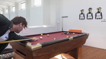 Mesa de billar con bolas, una persona jugando y adornos en la pared.