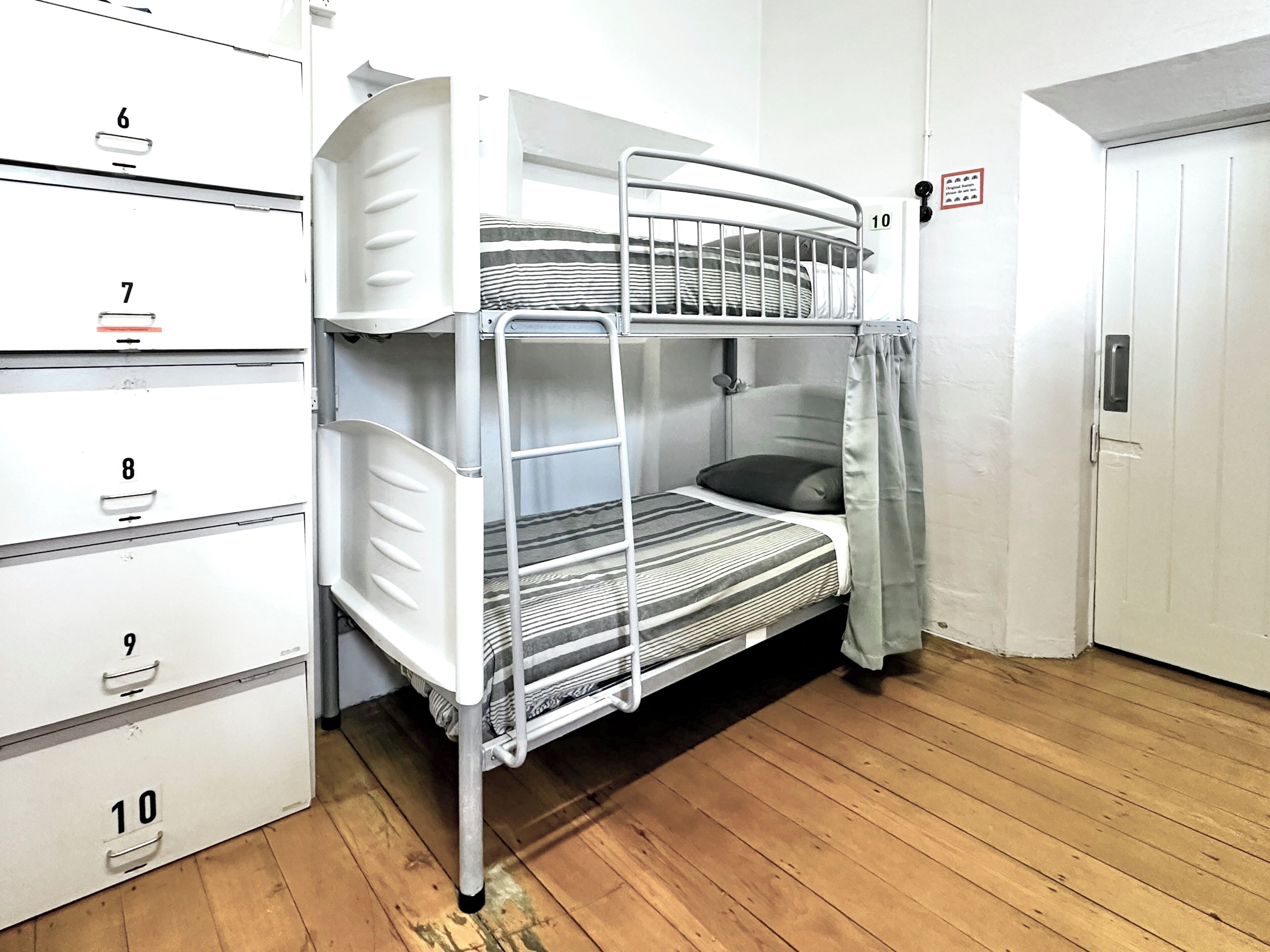 A bunk bed with a ladder, a door with a lock, and a set of numbered storage cabinets.