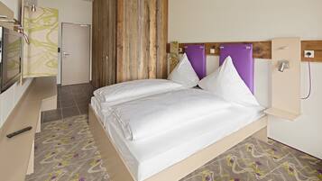 A modern hotel room with a bed, a TV, and a shower area.