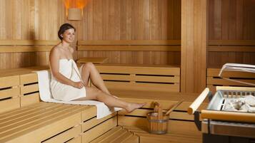 A sauna with wooden benches and a wooden table with a bucket and a towel.