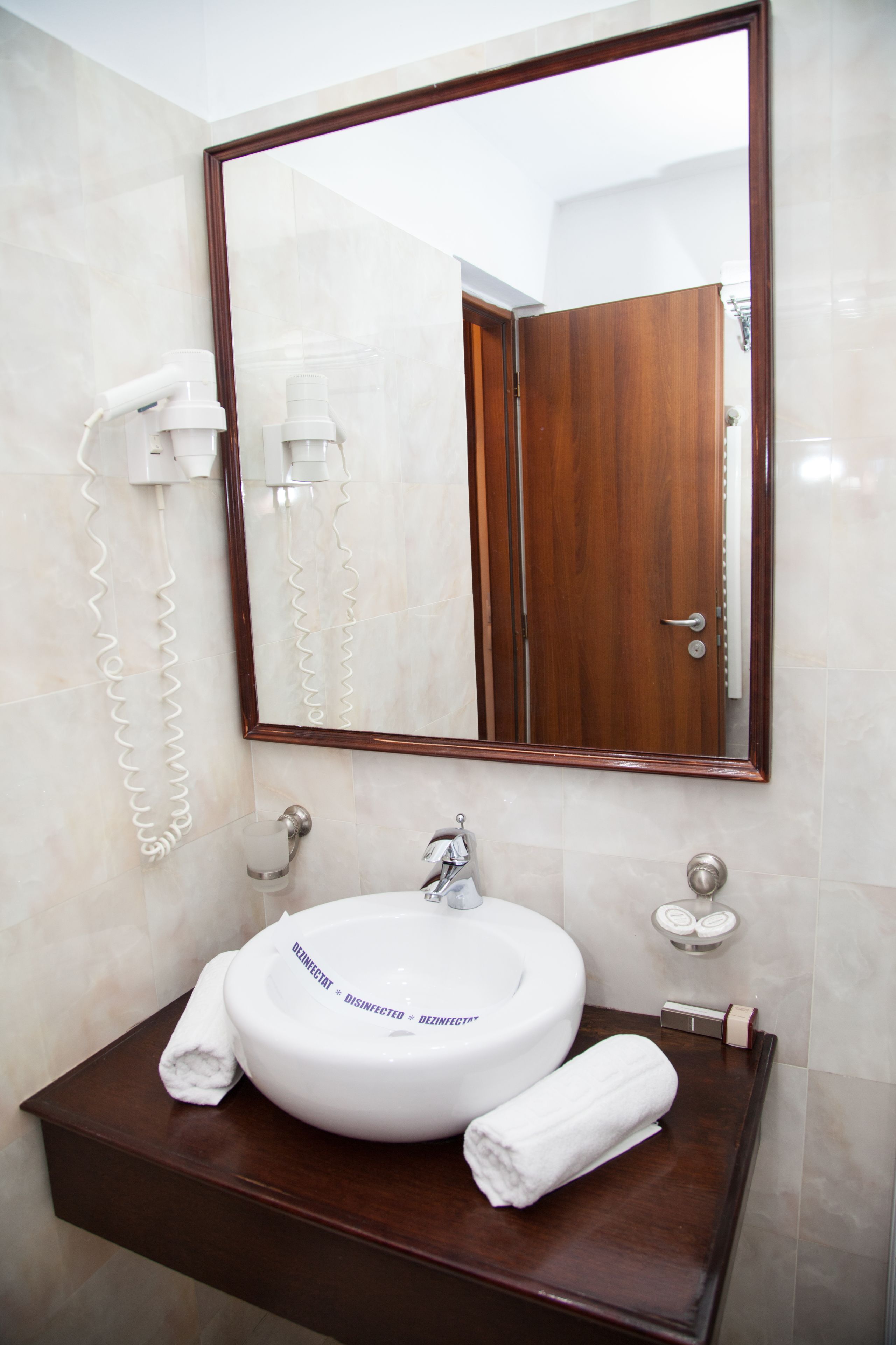 A bathroom with a white sink, a mirror, a wooden vanity, and a towel rack.
