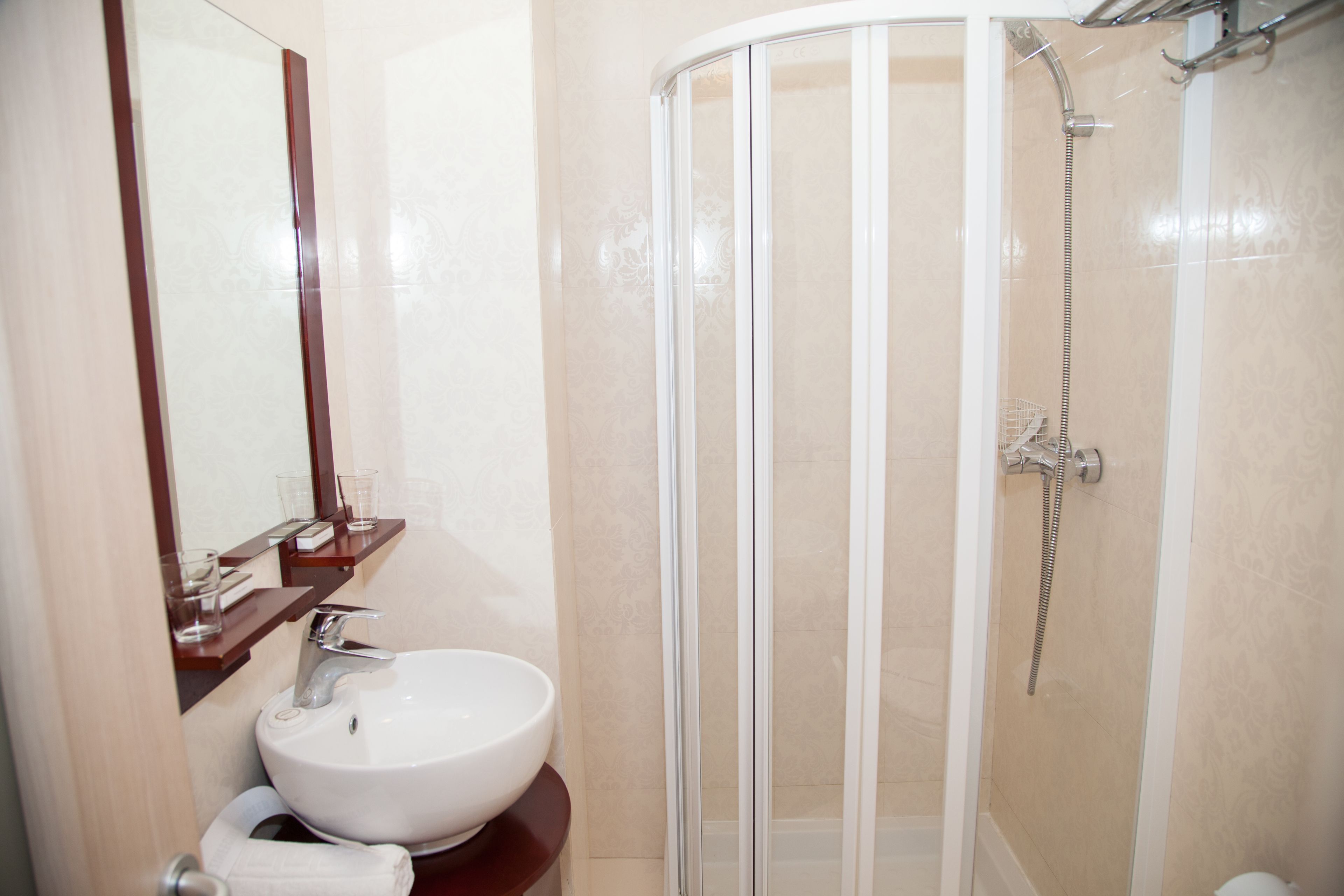 Une salle de bain avec un lavabo blanc, un miroir et une douche à parois de verre.