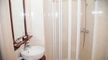 Une salle de bain avec un lavabo blanc, un miroir et une douche à parois de verre.