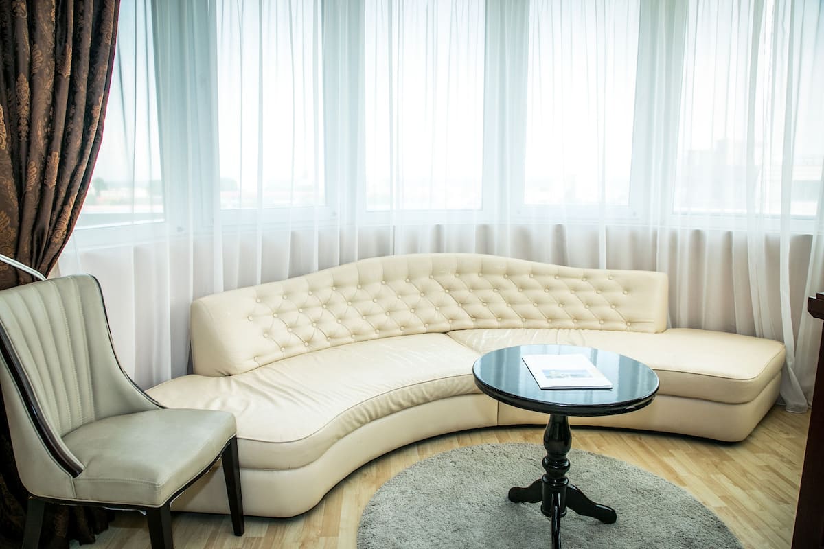 A modern living room with a curved beige sofa, a matching armchair, and a small round table.