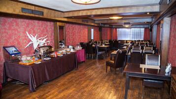 Espaço de refeições com várias mesas e cadeiras, um buffet e uma parede decorativa.