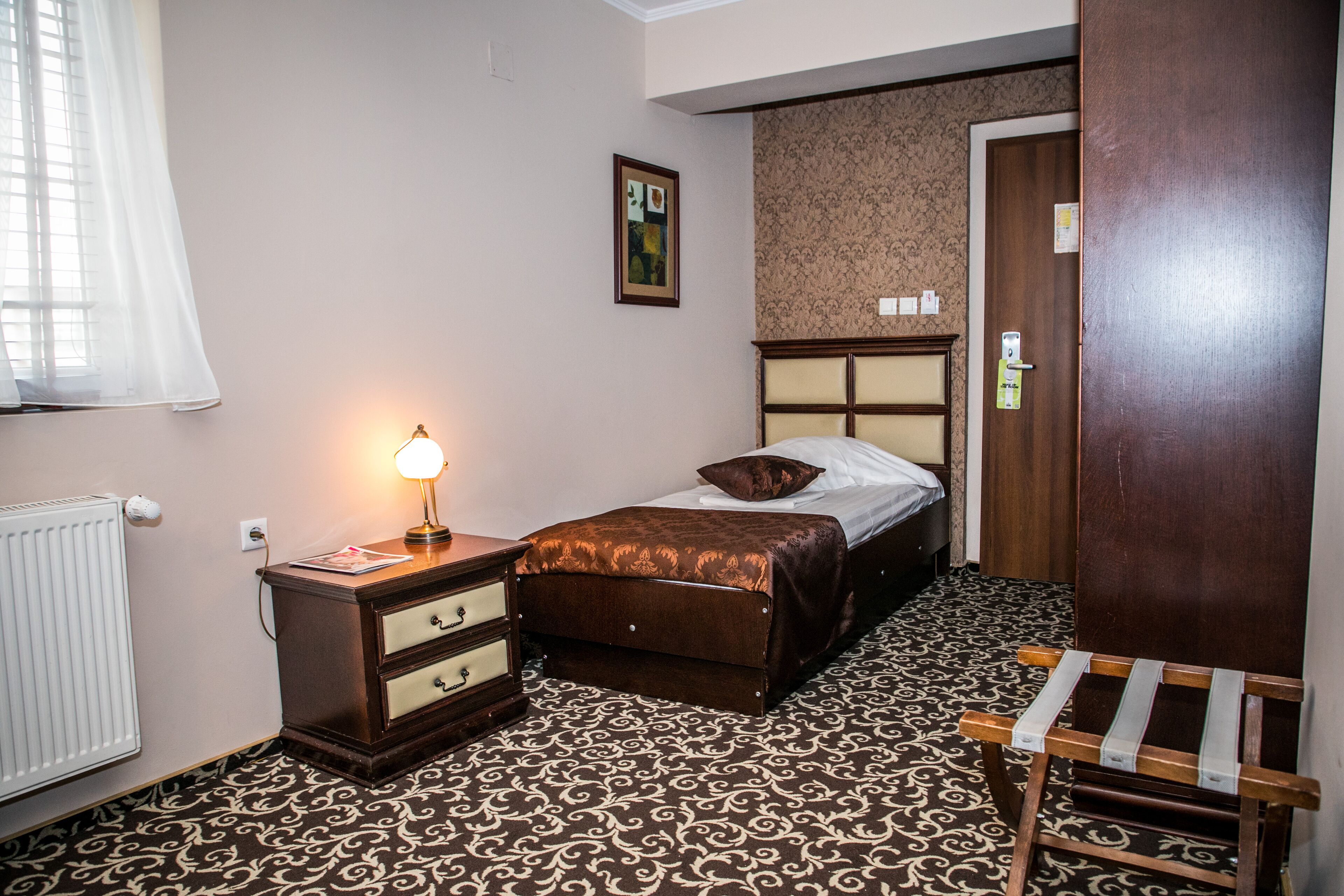 A bedroom with a bed, bedside table, lamp, and a chair.