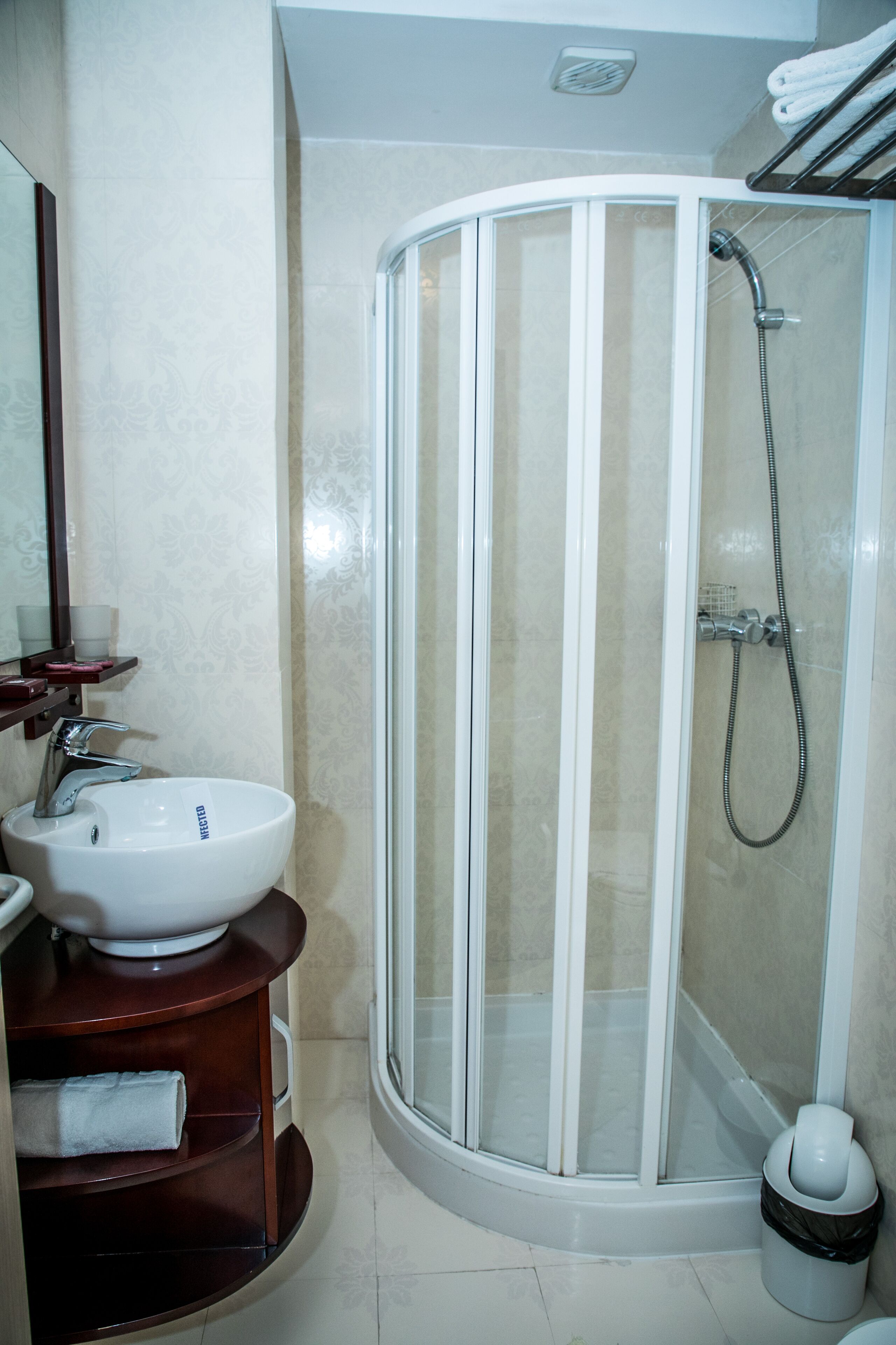 Une salle de bain avec un lavabo blanc, un miroir, une cabine de douche et un porte-serviettes.