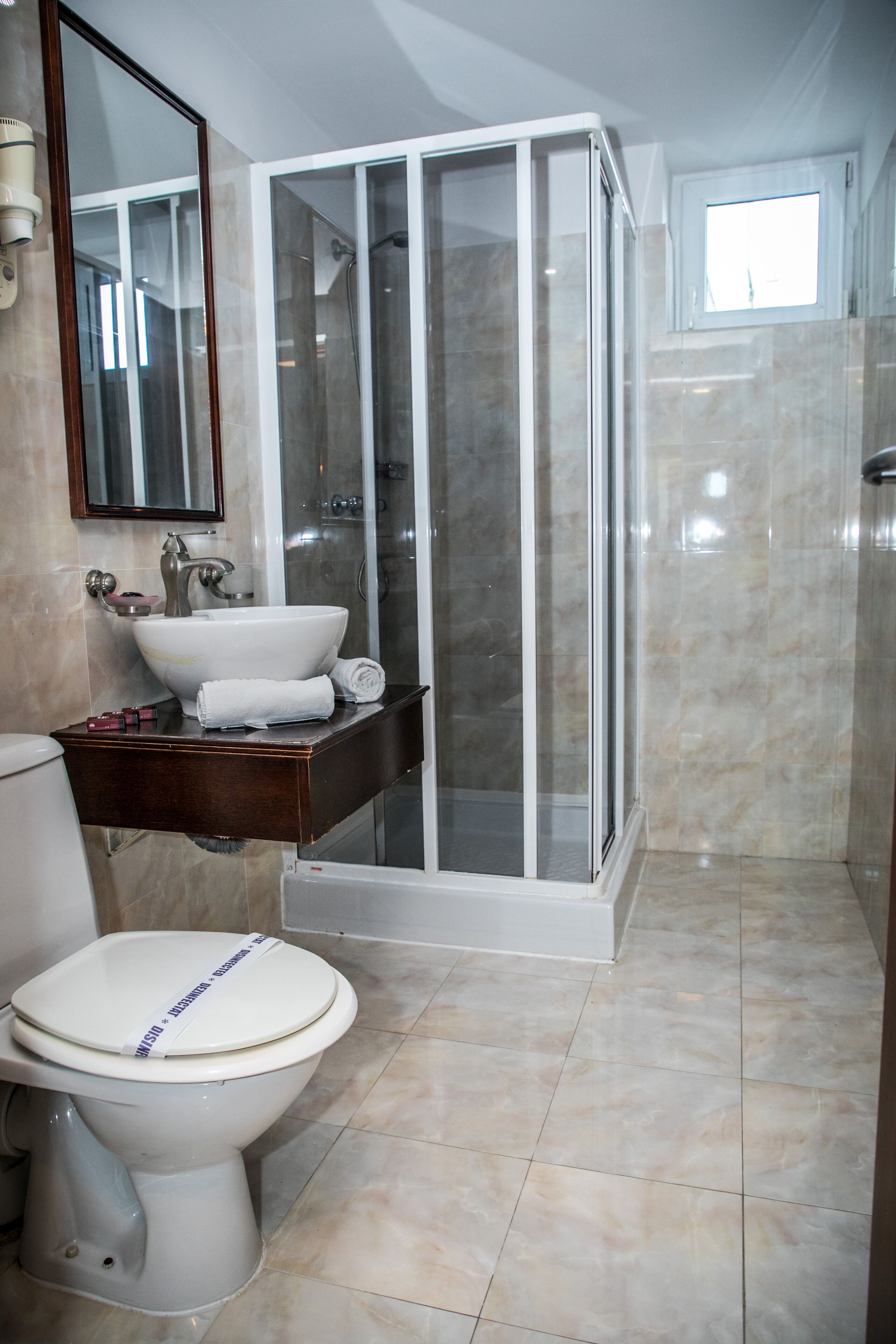 Een badkamer met een douchecabine van glas, een witte wastafel en een toilet.