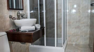 A bathroom with a glass-enclosed shower, a white sink, and a toilet.
