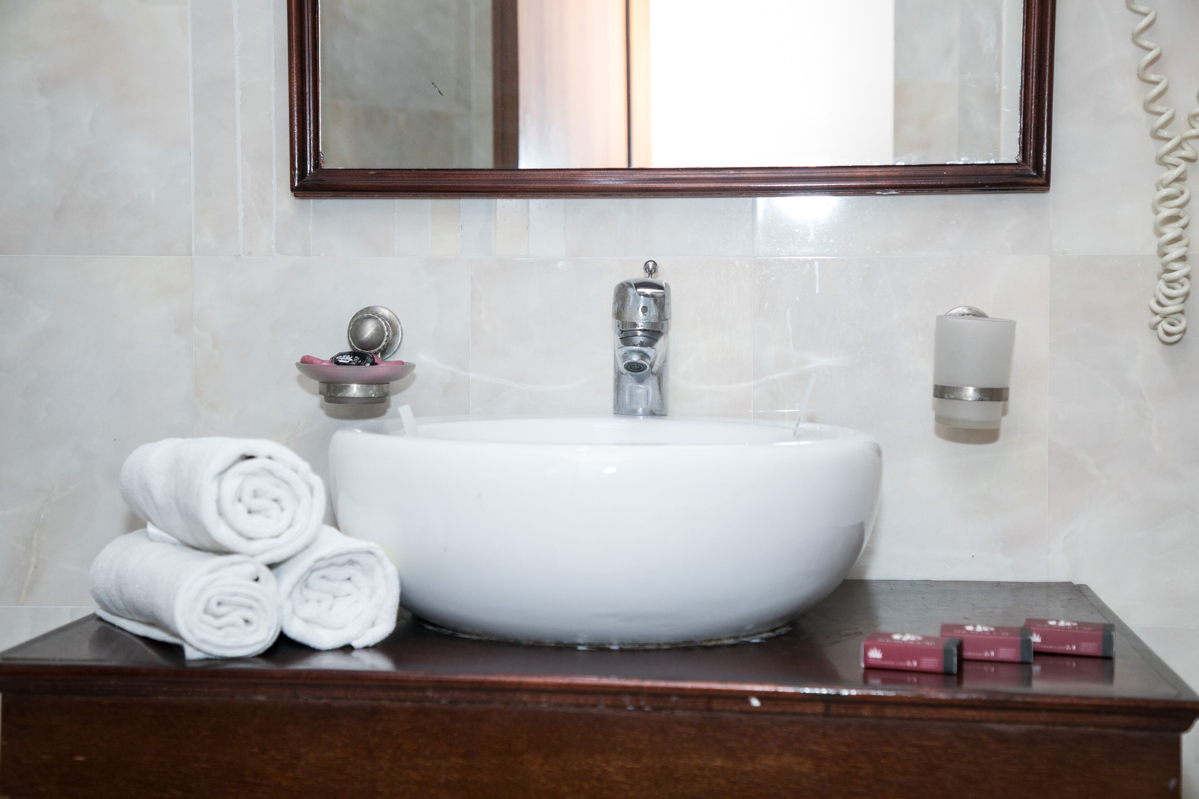 A bathroom with a white sink, a mirror above it, and a wooden vanity.