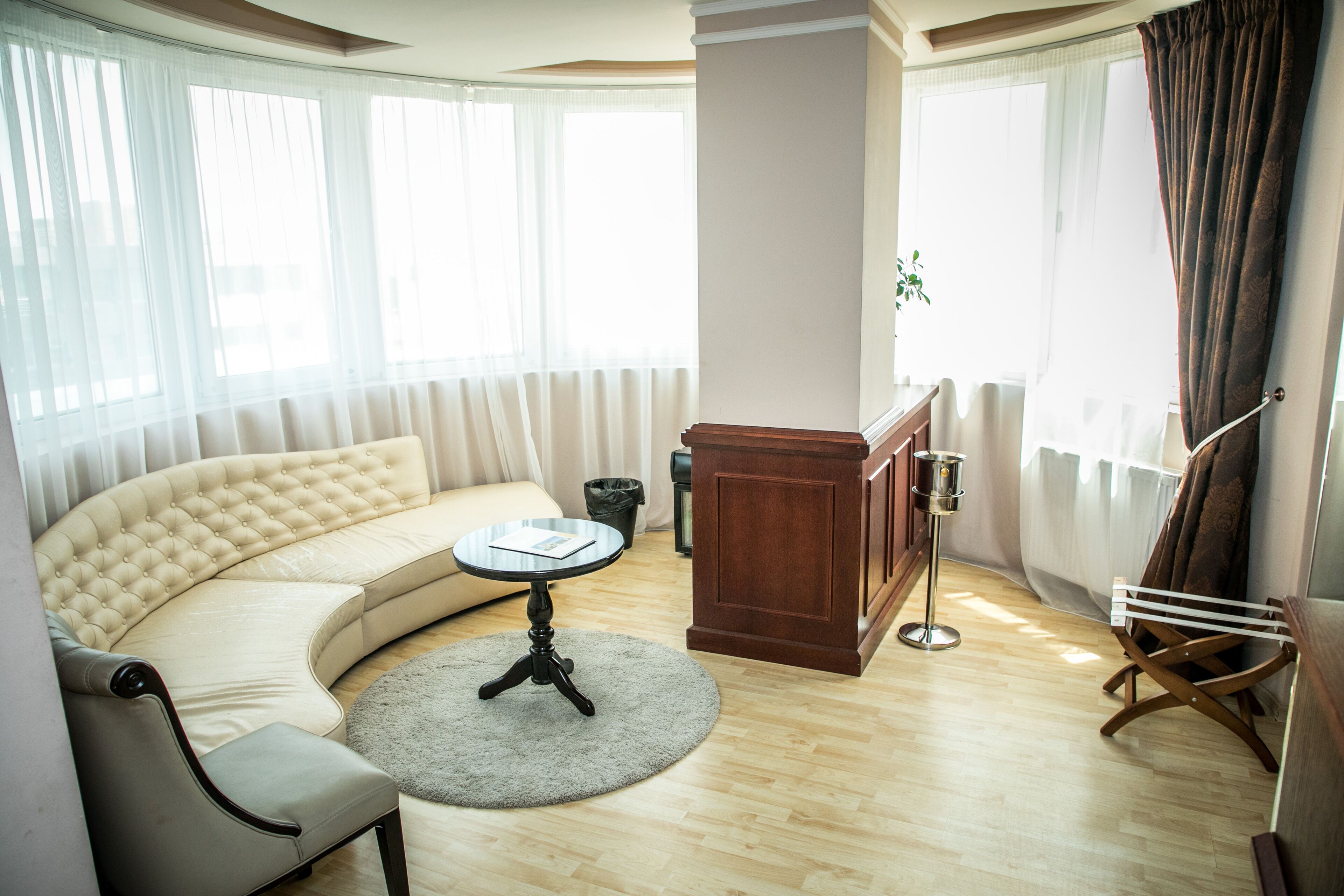 Una sala de estar moderna con un sofá curvo, una mesa de centro redonda y un mueble de madera.