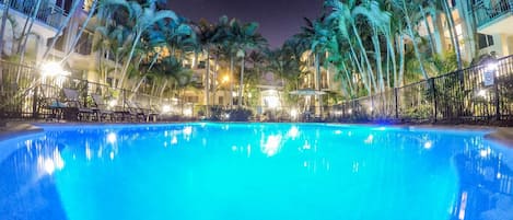 Una piscina al aire libre, sillones reclinables de piscina