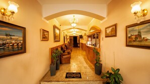 Vestíbulo de hotel con mostrador de recepción, zona de estar y un candelabro.