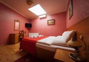 A hotel room with a bed, a desk, a chair, a lamp, and a television. - Hotel Askania (Prague)