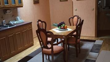 Un comedor con una mesa y sillas de madera, un frutero y una cocina con armarios de madera y una encimera.