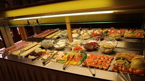 Un bufé con diversos alimentos, incluyendo carnes, quesos, frutas y verduras.