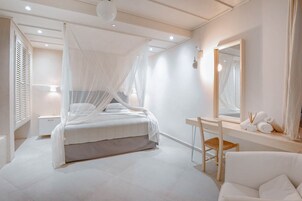 Un dormitorio con cama, mesita de noche, silla y espejo.