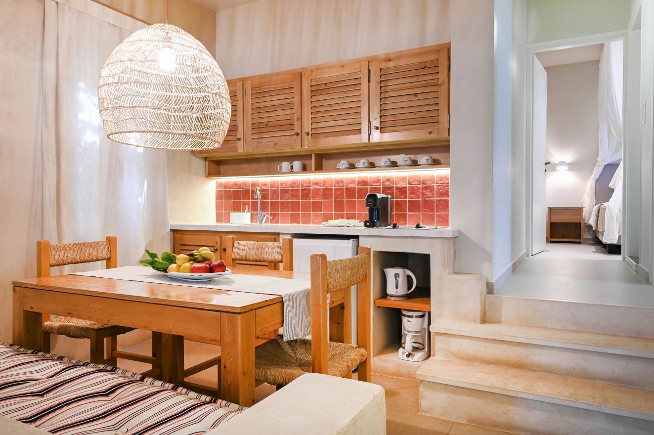 A cozy kitchen with wooden cabinets, a tiled backsplash, and a dining area with a table set for two.