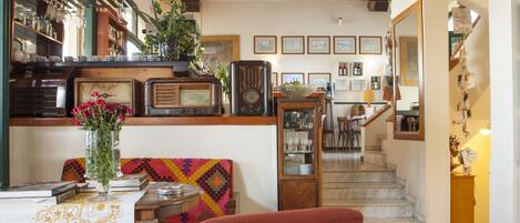 A cozy living room with a dining area, a staircase, and a kitchen area with vintage radios.