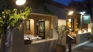 Un restaurant méditerranéen doté d’une terrasse, agrémenté de plantes en pot, et dont l’enseigne indique son nom.