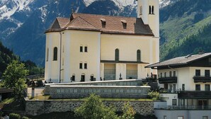 Une église dotée d’un clocher, se dressant sur un fond de montagnes enneigées.