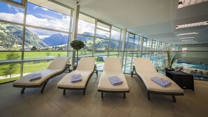 Un espace bien-être comprenant trois chaises longues, une piscine et une vue sur les montagnes.