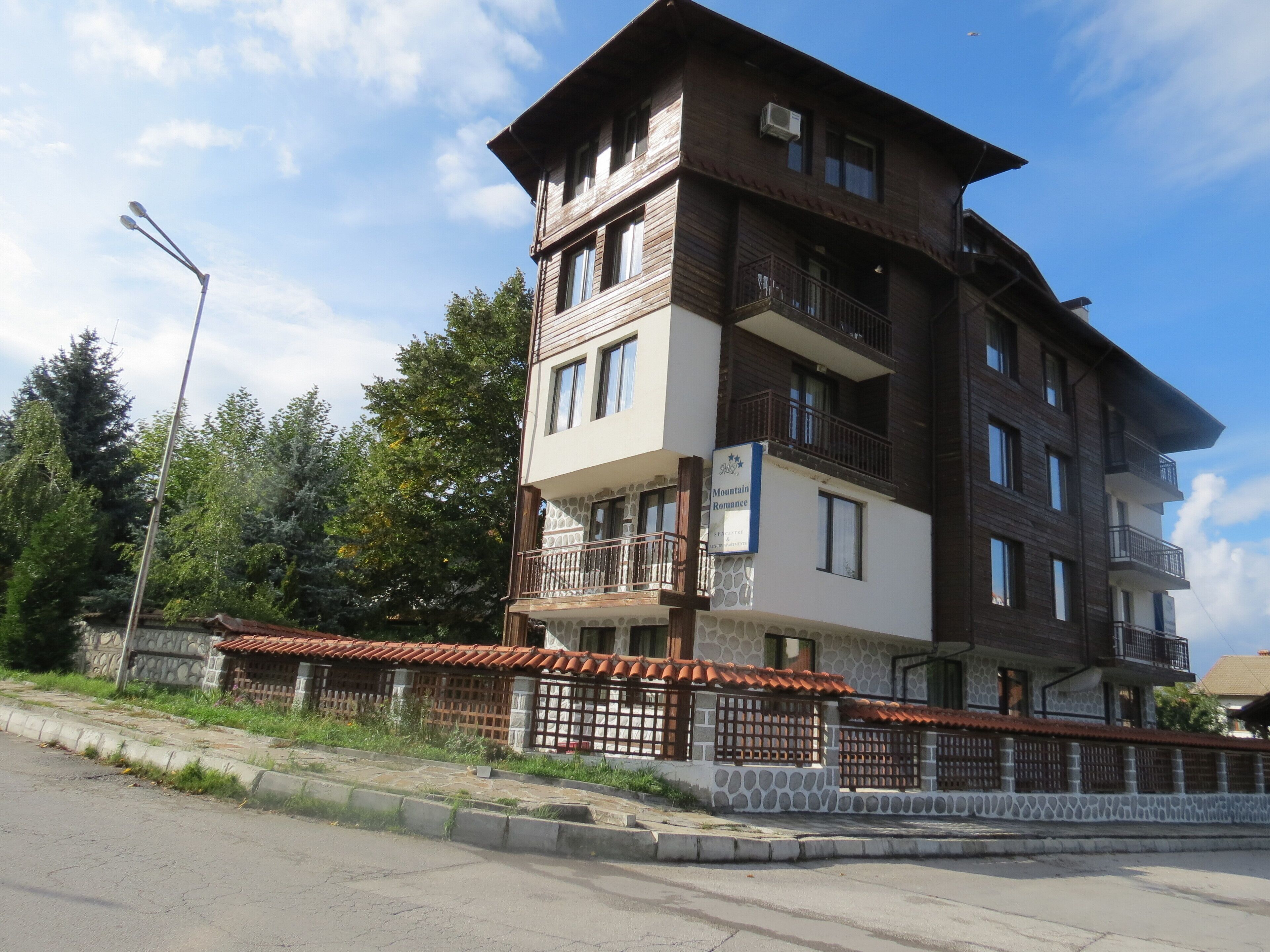 A multi-story building with balconies, a stone facade, and a sign indicating it is a hotel.