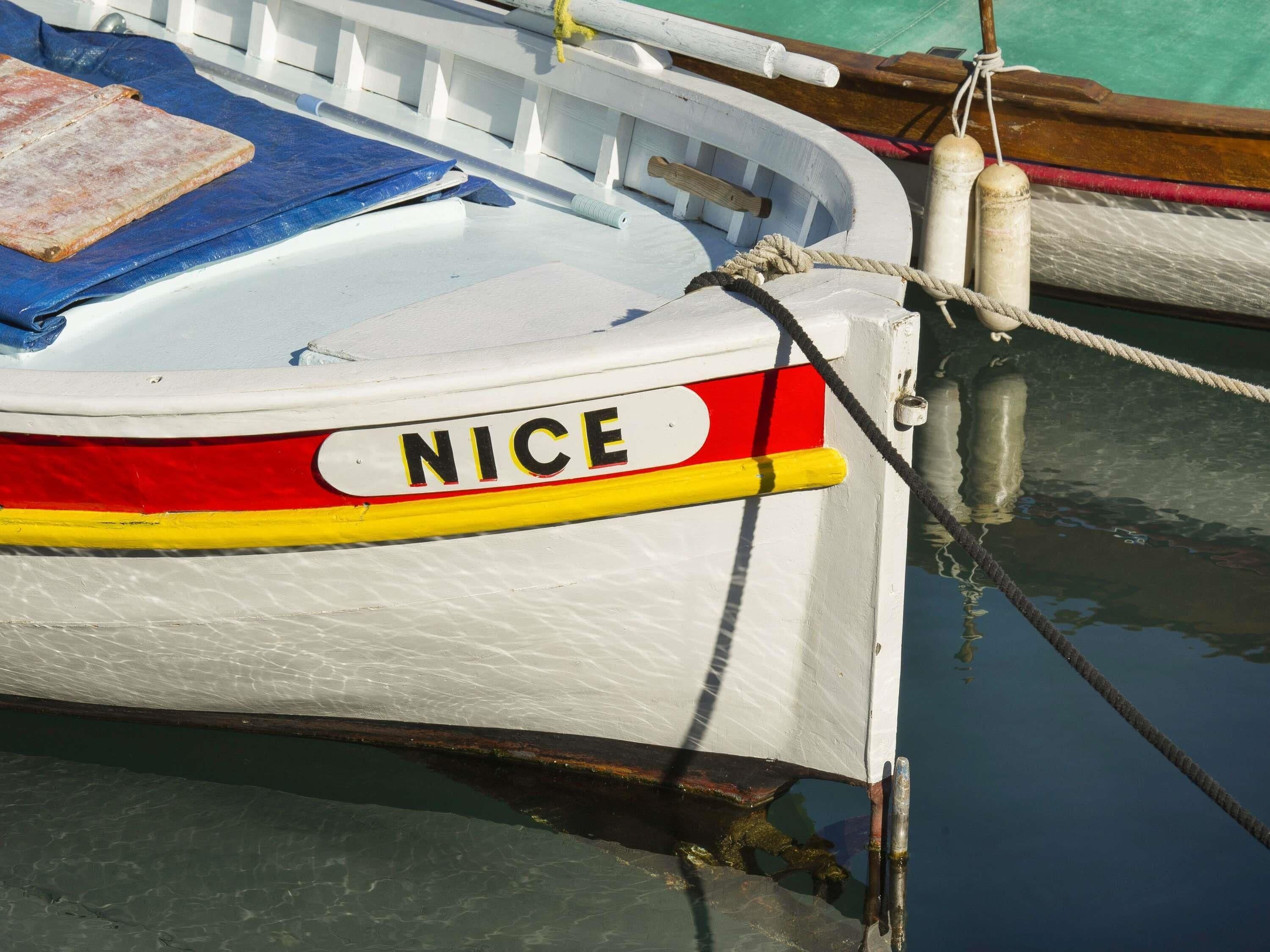 En båt med namnet ”NICE” låg förtöjd vid en småbåtshamn, med ett rep fastknutet vid en pollare.