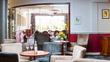 Un vestíbulo de hotel con zonas de estar, un mostrador de recepción y vistas al comedor.