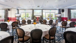 A conference room with round tables, chairs, and a projector screen. - George Albert Hotel & Spa (Dorchester)