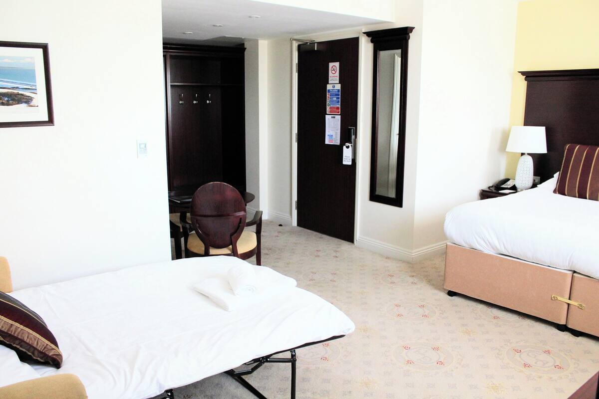 A hotel room with a bed, a desk, and a chair.