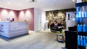 A spa and beauty reception area with a stone wall, a chandelier, and a reception desk. - George Albert Hotel & Spa (Dorchester)