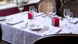 A dining area with a table set for four, large windows, and a view of the garden. - George Albert Hotel & Spa (Dorchester)
