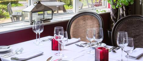 Comedor con mesa dispuesta para cuatro, ventanas amplias y vista al jardín.