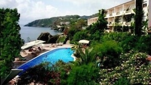 Un resort con piscina, exuberante vegetación y vistas al mar.