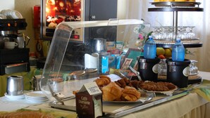 Un bufé de desayuno con diversos pasteles, bebidas y una estación de café.