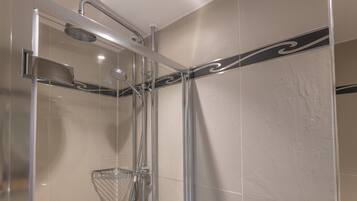 A modern shower with a glass enclosure, chrome fixtures, and a decorative black stripe on the wall.