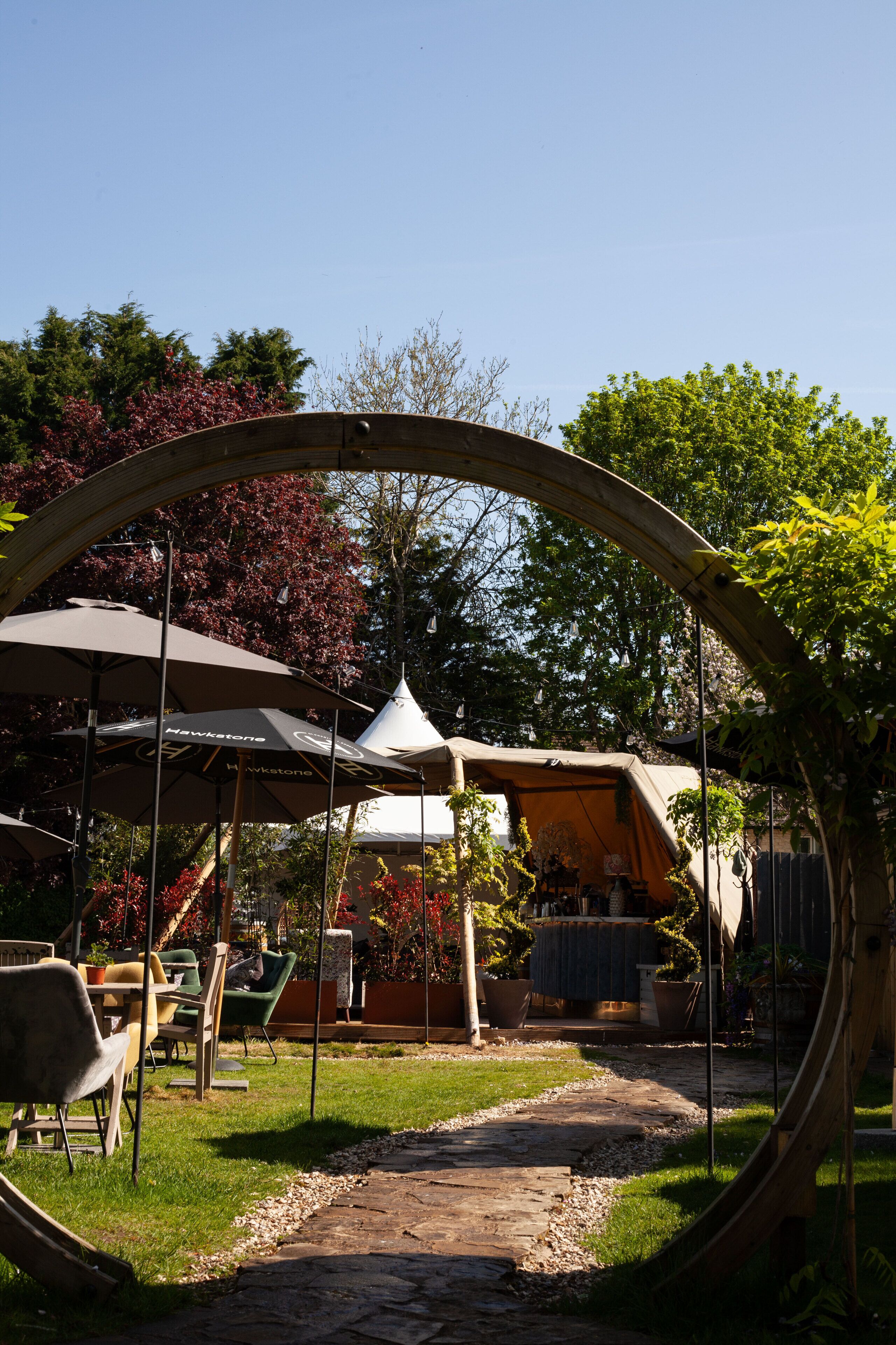 A garden with outdoor seating, a pergola, and a tent.