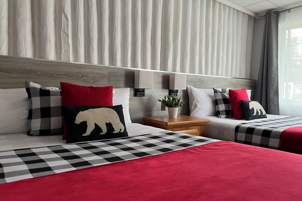 Habitación de hotel con dos camas, ropa de cama a cuadros y una variedad de almohadas.